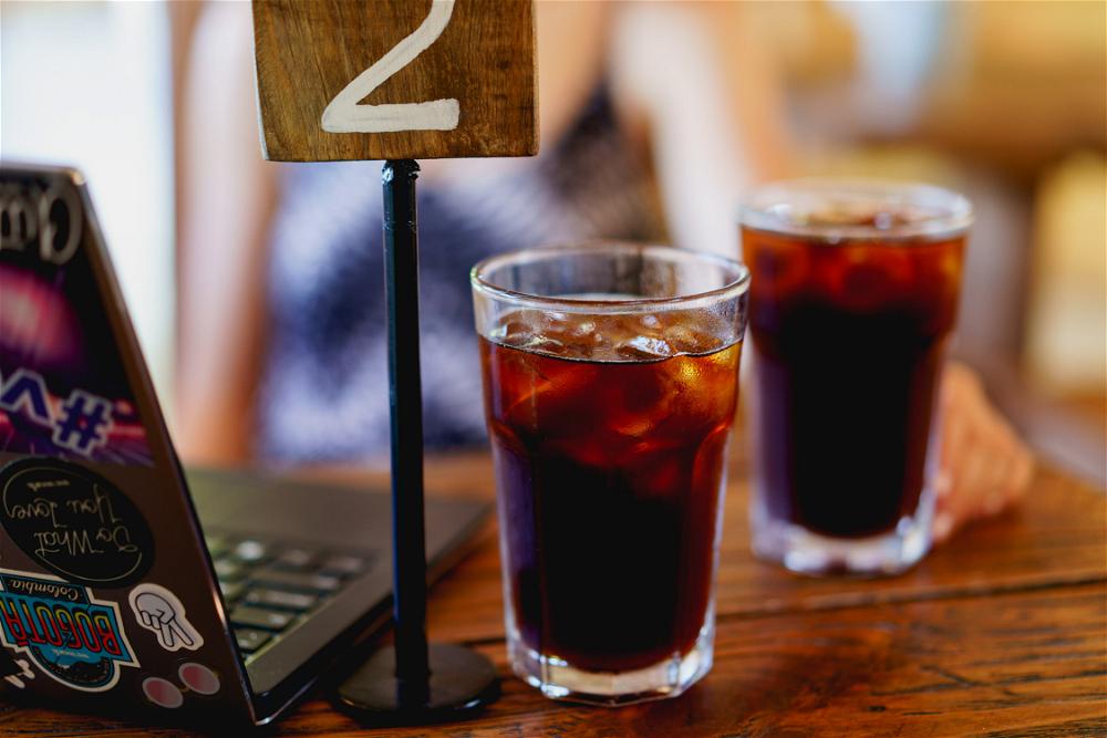 Two iced cold brew coffees in tall glasses next to a laptop