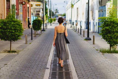 A woman in a dress walking down a street.