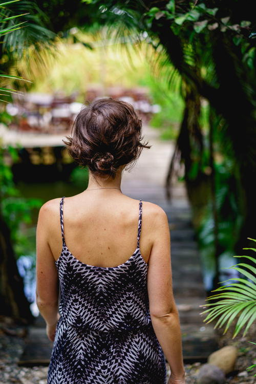 A woman walking down a path in a tropical forest.