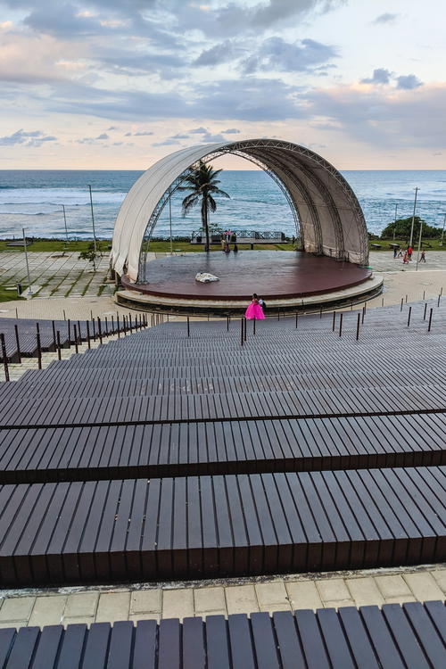 A person is sitting on a wooden bench in front of the ocean.