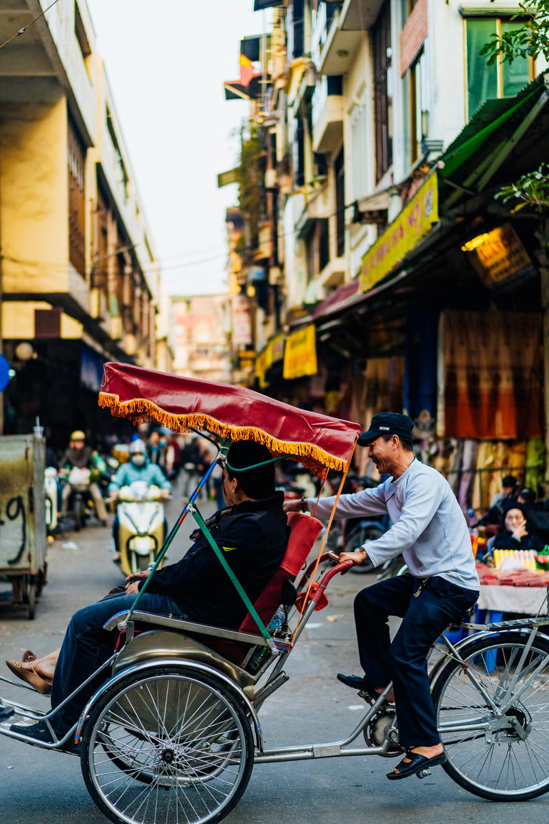 A man riding a rickshaw down a street.