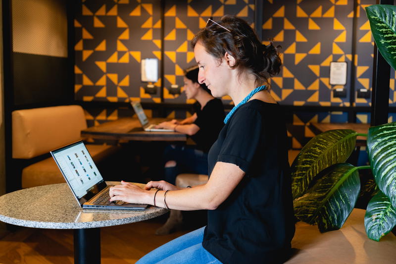 A woman working on a laptop in a coffee shop.