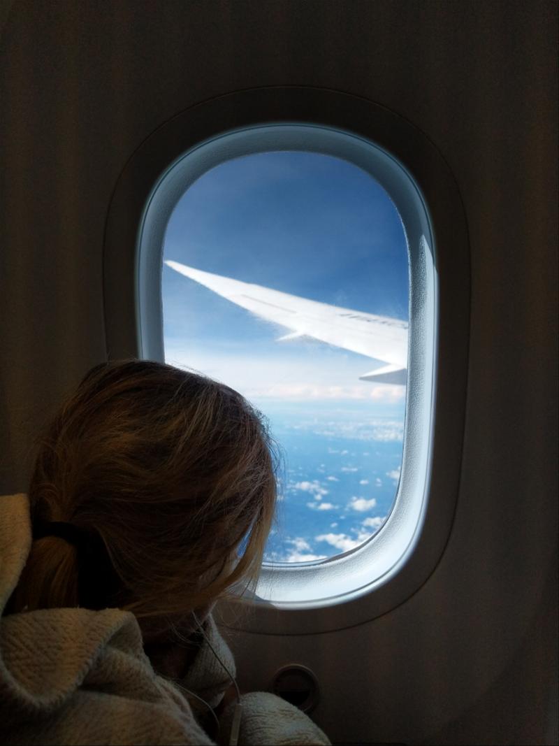 A woman looking out the window of an airplane.