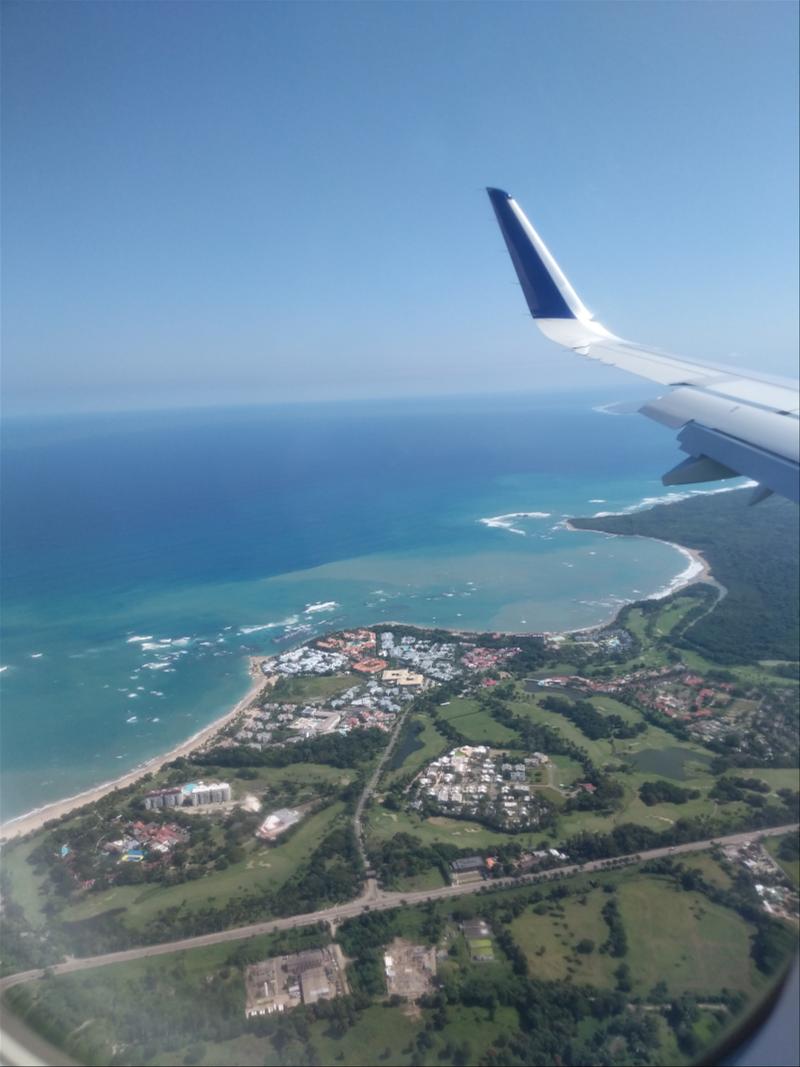 An airplane wing with a view of a beach and ocean.