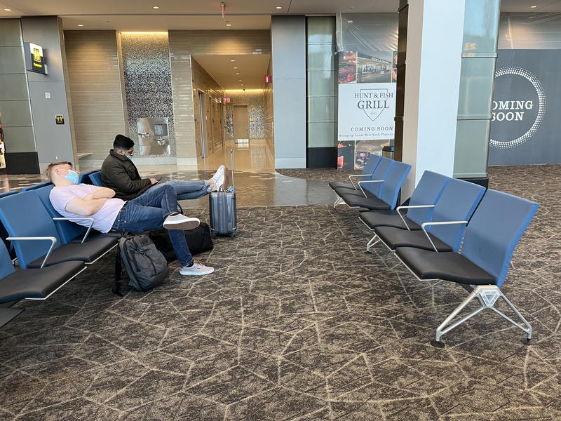 A group of people sitting on chairs in an airport.