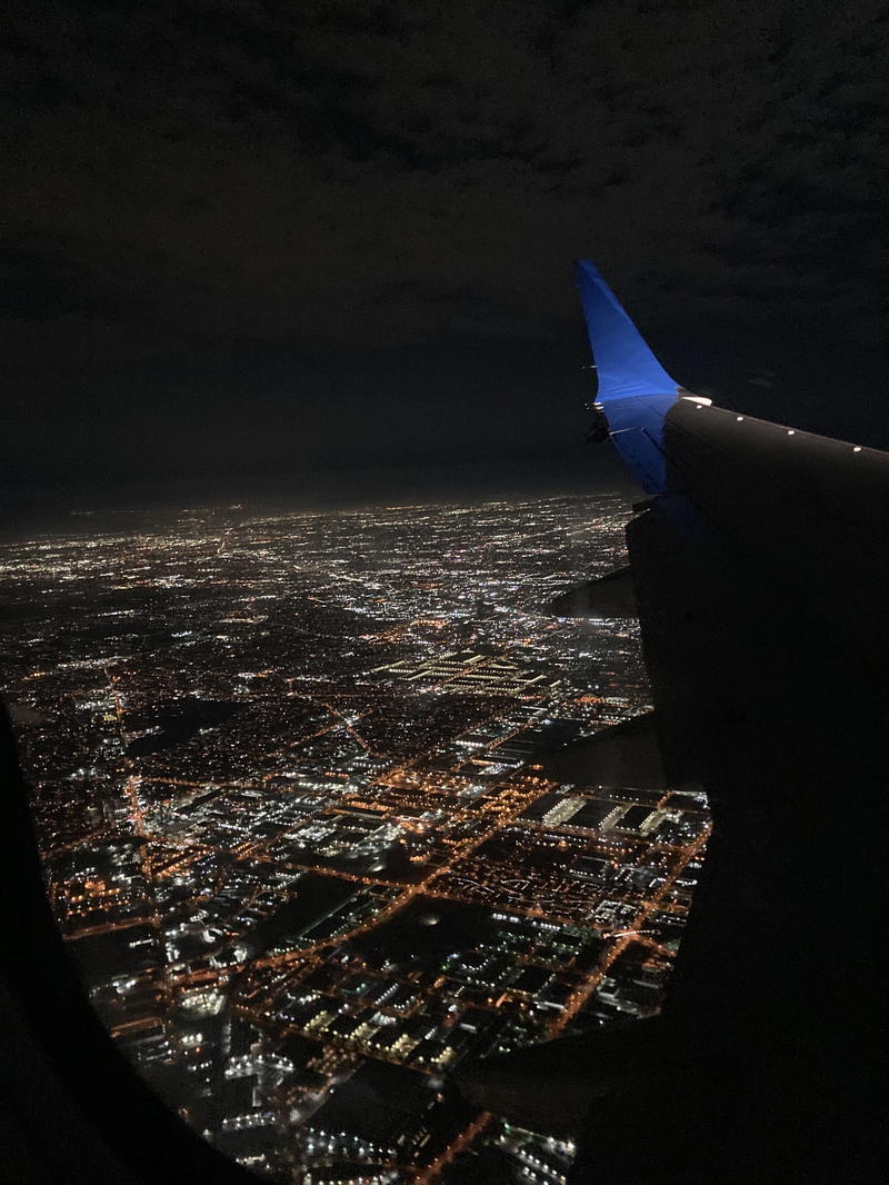 An airplane wing looking out over a city at night.