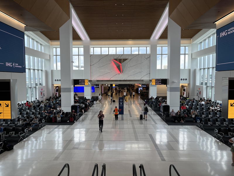 The inside of an airport with many people walking around.