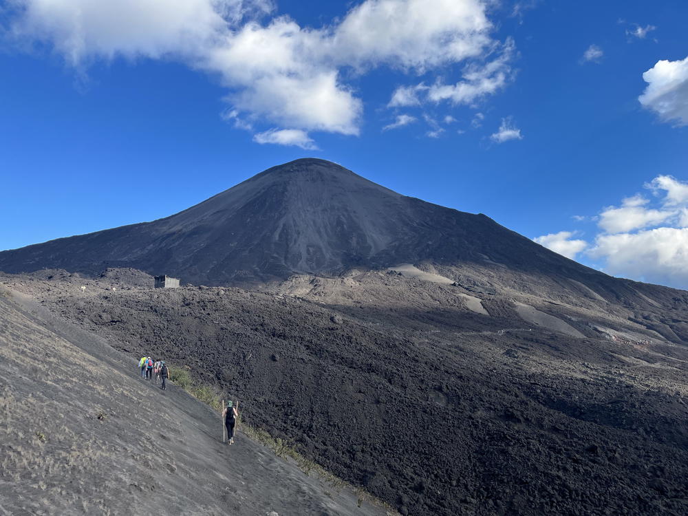 A group of people walking up the side of a mountain.