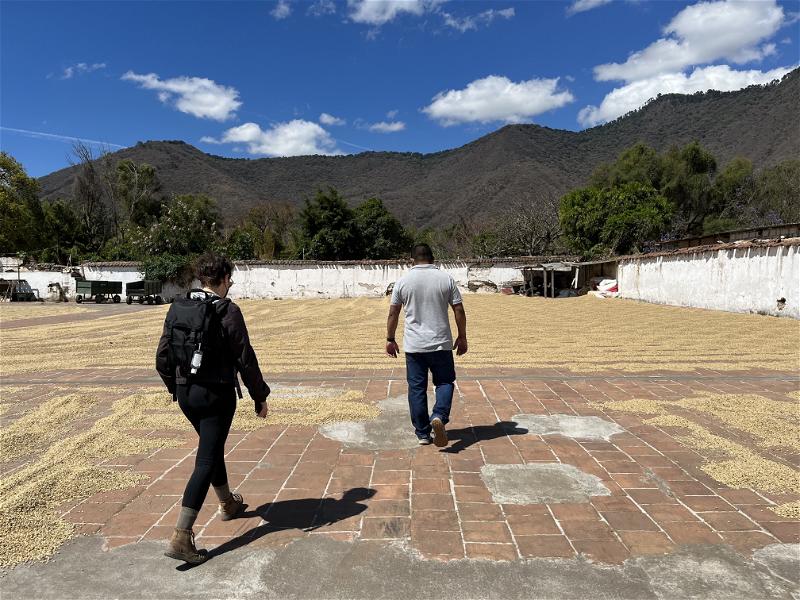 Two people walking through a Guatemalan courtyard with mountains in the background.