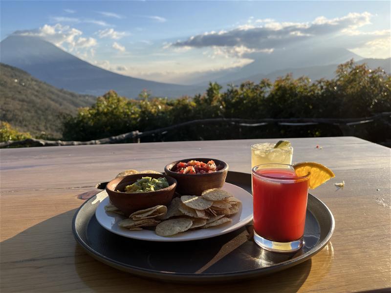 A plate of chips and guacamole with a view of a Guatemalan volcano.