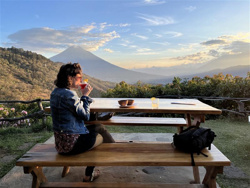 A woman sitting at a table with a view of a Guatemalan mountain.