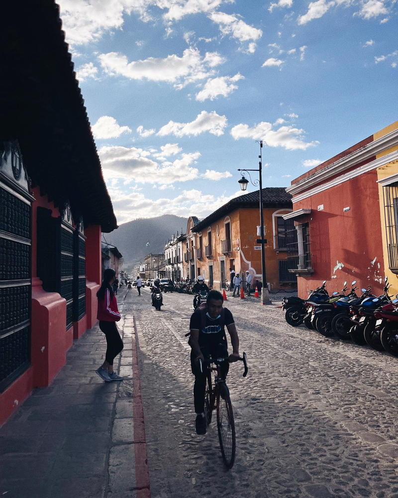 A person riding a bicycle down a cobblestone street.