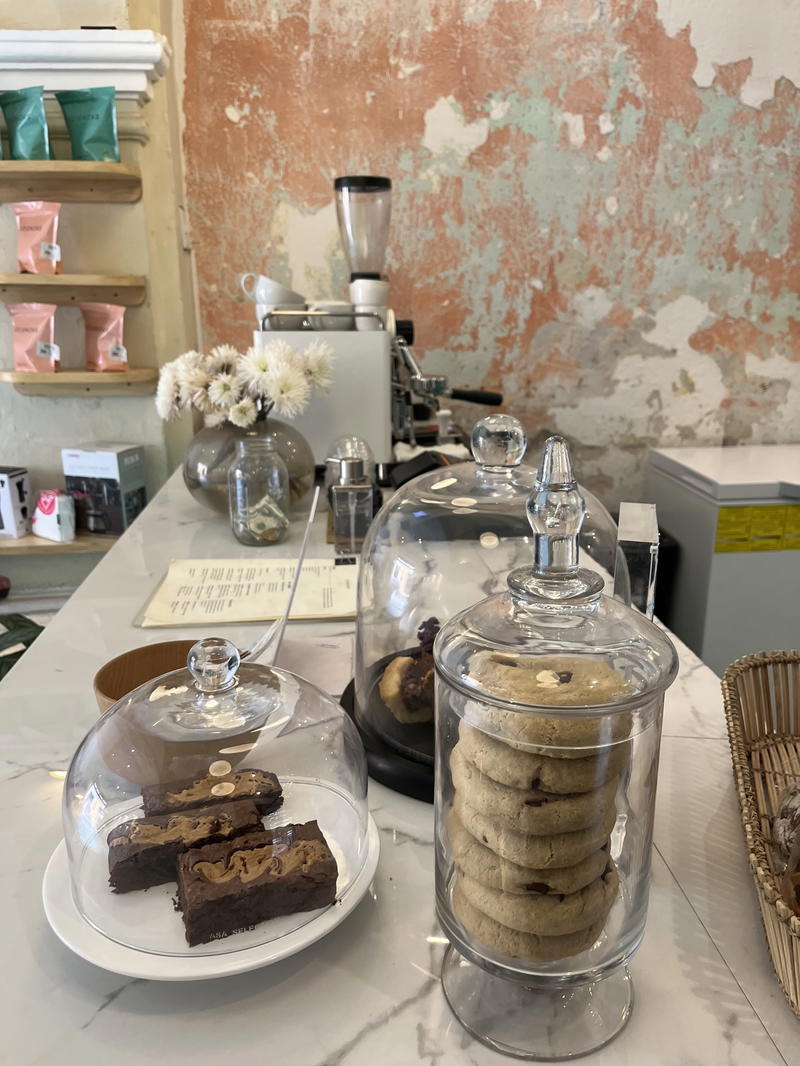 A coffee shop with a counter full of cookies and pastries.