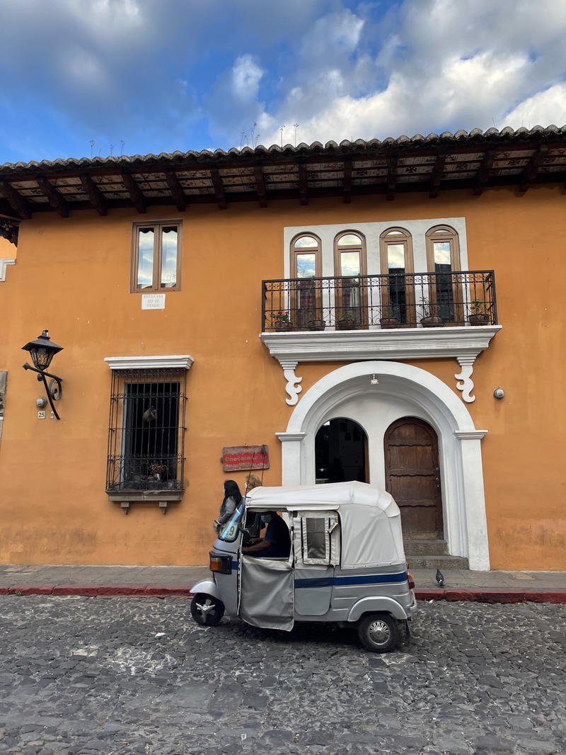 A tuk tuk parked in front of an old building in Guatemala.