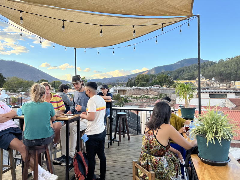 A group of people sitting on a rooftop in Guatemala with mountains in the background.