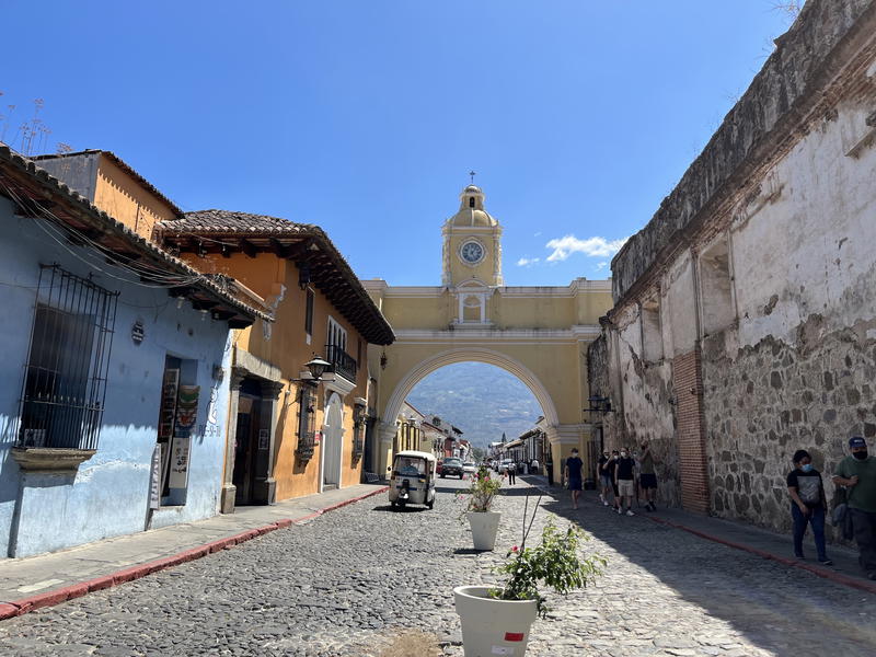 A cobblestone street in Guatemala with a clock tower in the background.