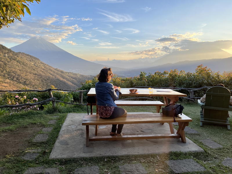 A woman sits at a table in front of a mountain in Guatemala.