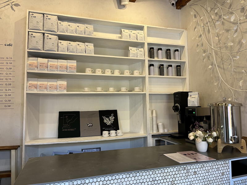 A coffee shop with a white counter and shelves showcasing Guatemalan beans.