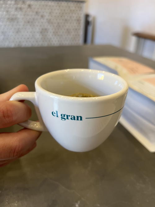 A person holding a cup of coffee from Guatemala with the word el gran written on it.