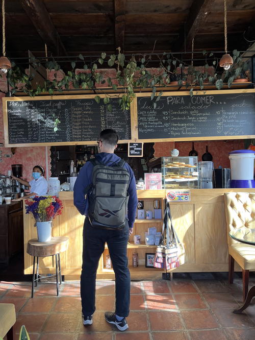 A man with a backpack standing in front of a coffee shop in Guatemala.