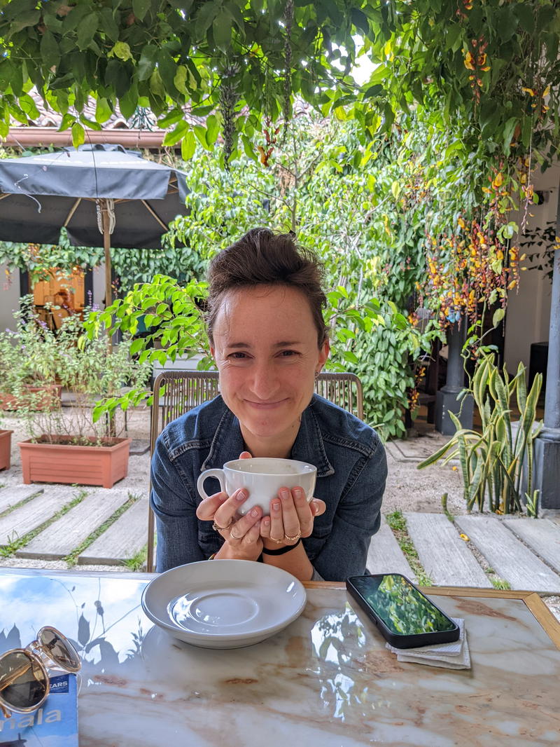 A person sitting at a table in Guatemala with a cup of coffee.