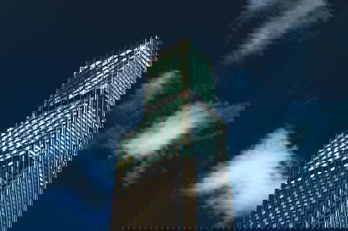 A tall building in Hong Kong lit up at night.