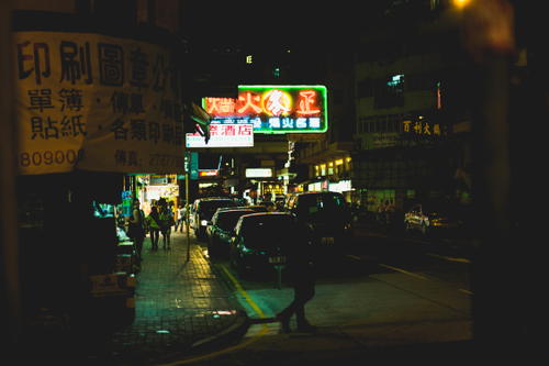 A person strolling through Hong Kong's city street at night.