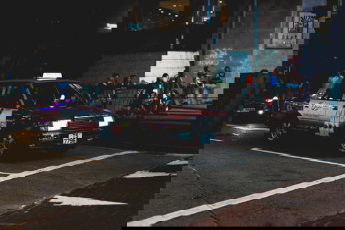 A Hong Kong taxi cab driving down the street.