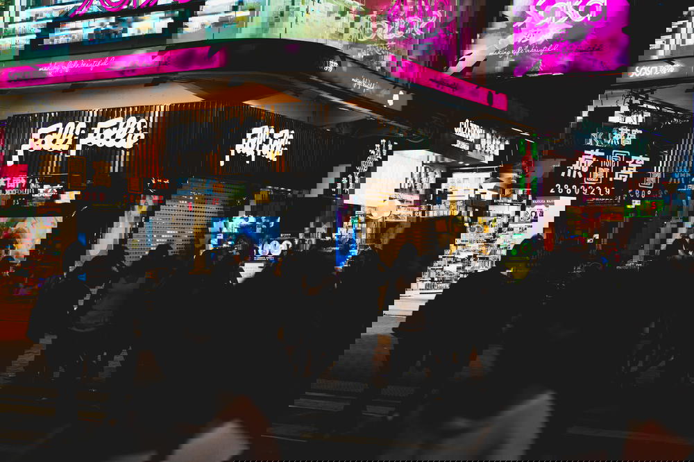 Neon signs behind a crowd of people on a busy street