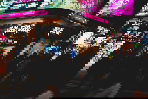 A crowd of people walking down a Hong Kong street at night.