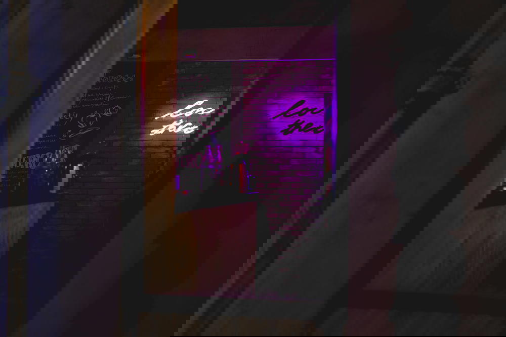 Neon sign looking through a window of a closed store at night