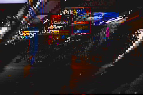 A person walking down a Hong Kong city street at night.