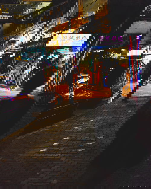 A person walking down a street at night in Hong Kong.