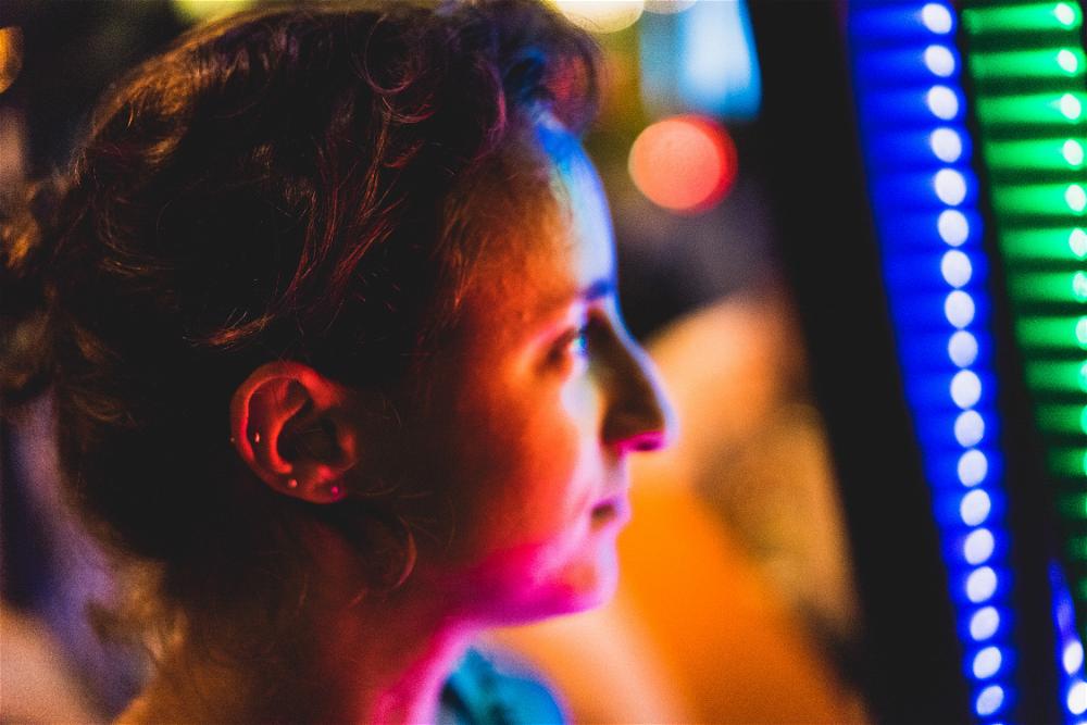 A woman in Hong Kong staring at a vibrant arcade machine.
