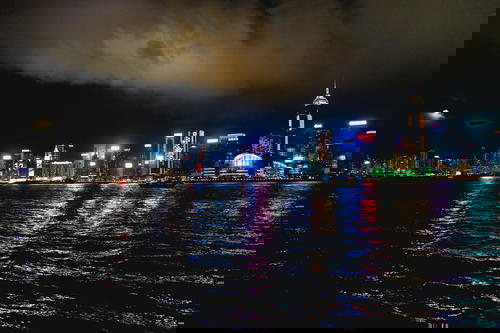 Hong Kong city skyline reflected in a body of water.