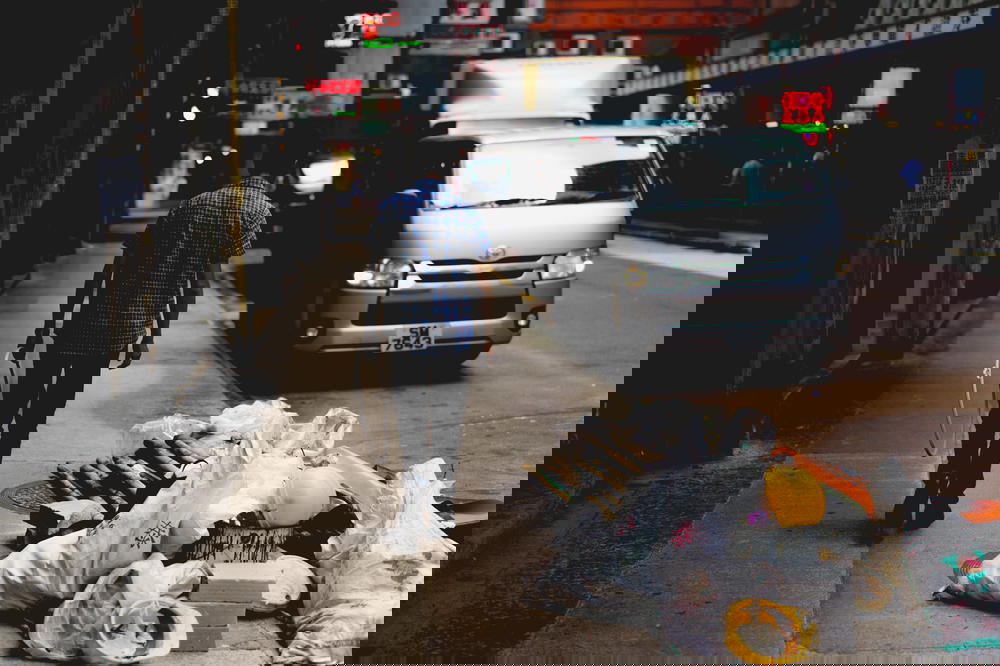 Man next to rubbish on the street on a Hong Kong Street