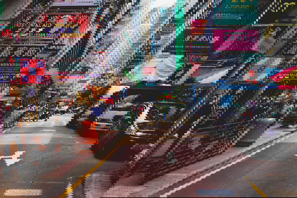 Busy street with cars, pedestrians and neon signs in Hong Kong