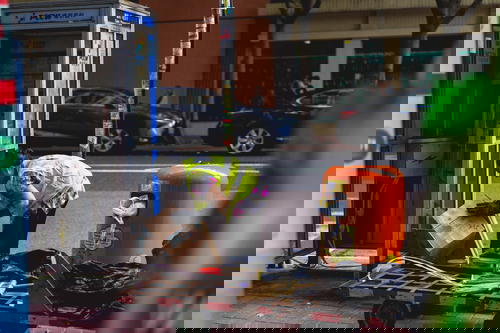 A woman in Hong Kong is placing boxes on a cart near a phone booth.