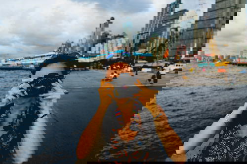 A woman capturing Hong Kong's cityscape with a camera.