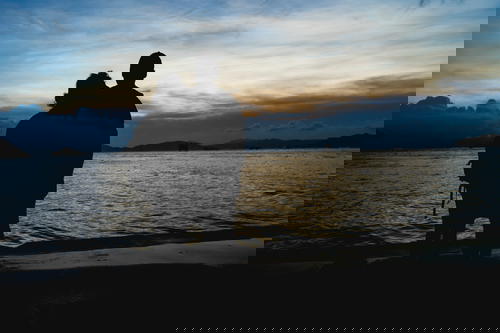 A silhouette of a couple standing by the Hong Kong water.