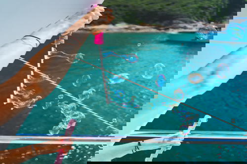 A woman enjoying a peaceful moment blowing bubbles on a boat in Hong Kong.