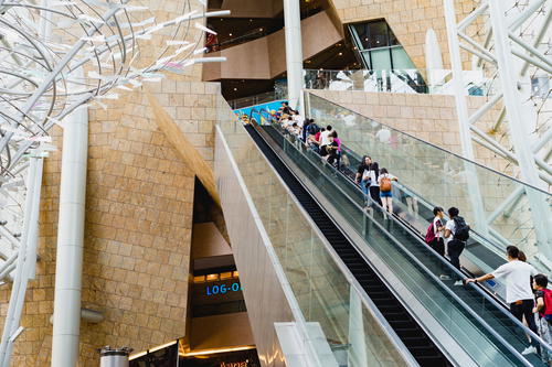 People walking down a shopping mall escalator in Hong Kong.