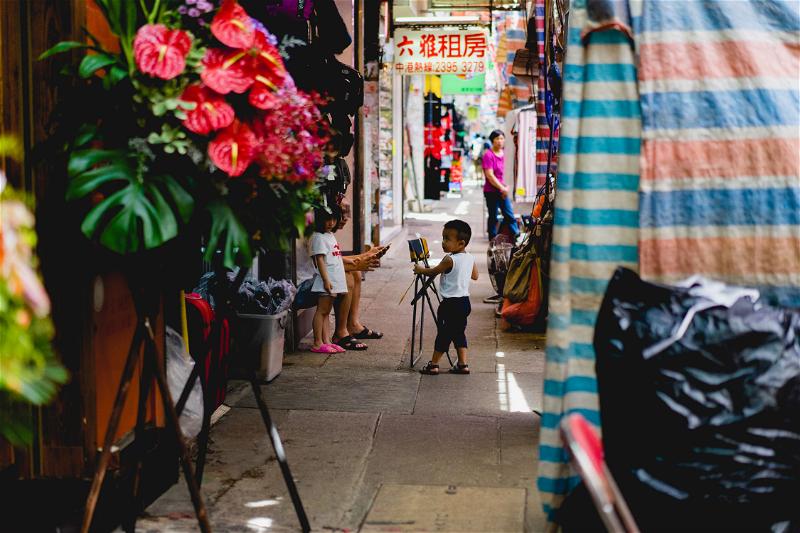 A child is strolling through a narrow Hong Kong alleyway.