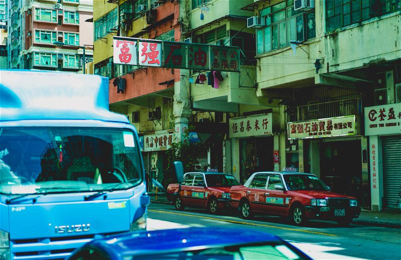 A blue truck driving down the streets of Hong Kong.