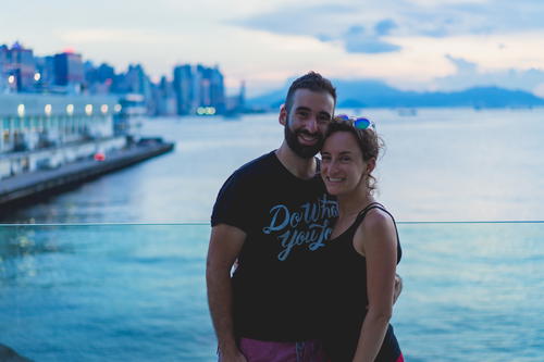 A man and woman posing for a photo in front of the water in Hong Kong.