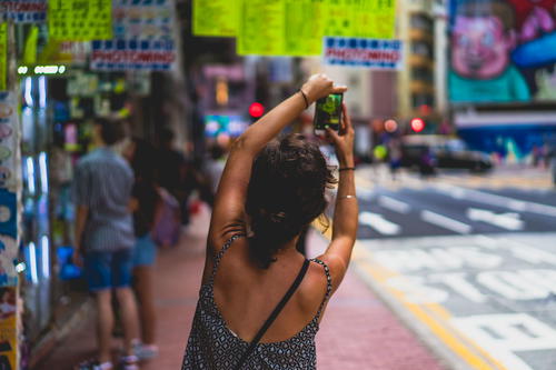 A woman is taking a picture of a street sign in Hong Kong.