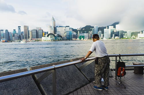 A man admiring Hong Kong from a railing.