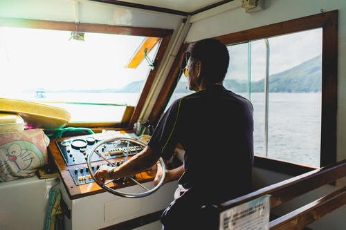 A man navigating the steering wheel of a boat in Hong Kong.