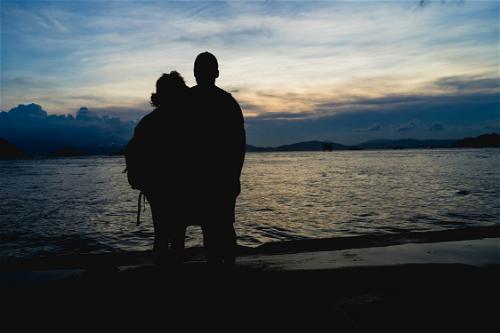 A silhouette of a couple standing by the water at sunset in Hong Kong.