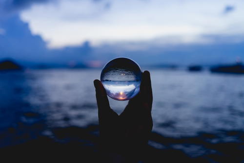 A person holding a glass ball in front of Victoria Harbour, Hong Kong.